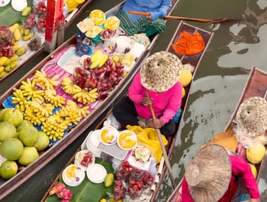 High angle view of vendors selling fresh tropical fruits from wooden boats at a Thai floating market.