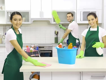a couple of people in aprons cleaning a counter