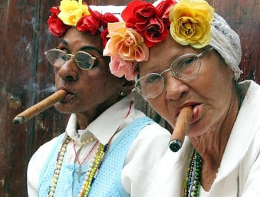 two elder Santeria brujas wearing white and smoking cigars