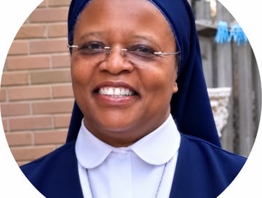 Smiling African American Catholic nun in a blue and white habit wearing glasses.