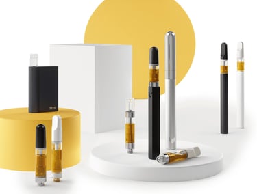 A collection of cannabis oil vape cartridges and battery pens on white and yellow displays.