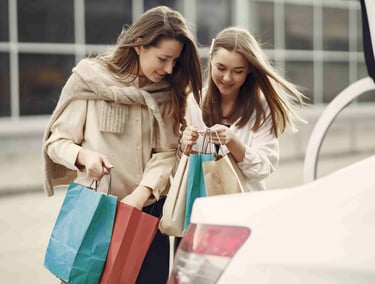 Two smiling women loading colorful bags into a Goa airport taxi