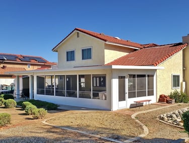 Two story yellow home with large white screened in patio.