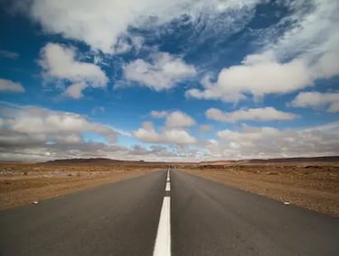 Empty desert road with white lines disappearing into the distance on Ultimate Sahara road trip