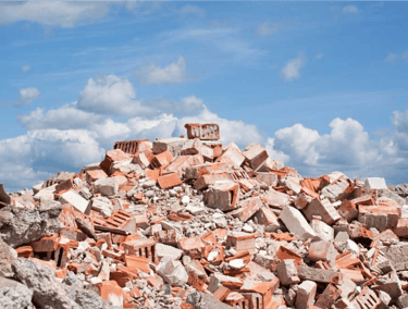 Enorme monte de entulho com restos de tijolos e concreto sob o céu, indicando necessidade de locação de caçamba para remoção