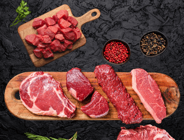 Bœuf halal cru : steaks et morceaux variés sur planche avec épices et herbes fraîches.