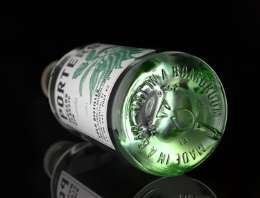 Green gin bottle with reflection lying down on black background