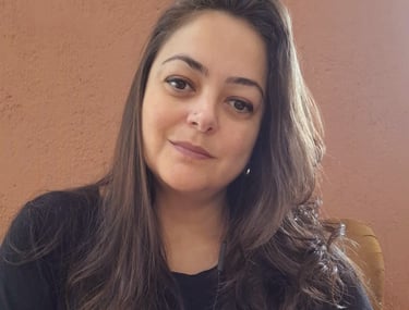 . Psicóloga Marcia Lhamas em seu espaço de atendimento online, cercada por plantas e livros, em atmo