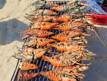 Fresh seafood lunch served on a sandbank during Safari Blue Zanzibar tour, including lobster, fish, and tropical fruits