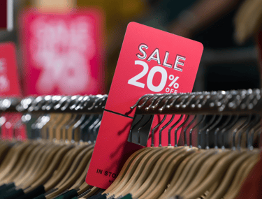Sale sign on a rack of clothing to symbolise AI in retail