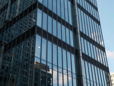 A modern glass building reflecting a clear blue sky, representing growth and innovation in an international tech-focused city center.