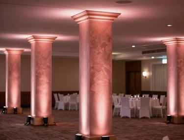Professional photography of a light-filled ballroom in a North American / US venue, with elegant rose gold and pink uplighting accentuating the columns.