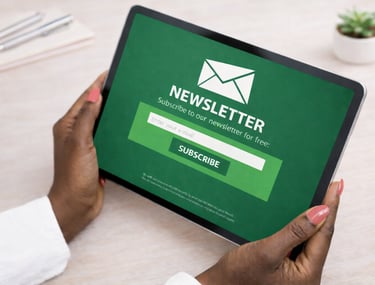Person holding a tablet displaying a newsletter subscription screen