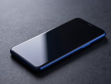 High-contrast shot of a sleek Android smartphone sitting on a dark grey surface, reflecting blue ambient light. Minimal and sophisticated.