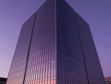 Low-angle architectural shot of a futuristic energy building in a North American setting with glass walls reflecting a deep purple sunset.