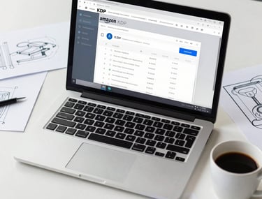 A workspace view showing a laptop with the Amazon KDP dashboard open, surrounded by design sketches and a cup of coffee on a white desk.