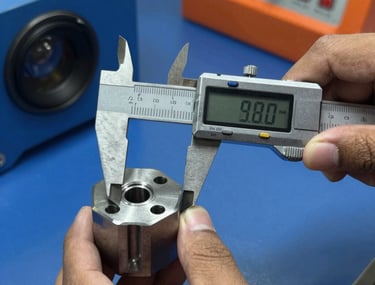 Close-up of a high-precision metal part being measured by a digital caliper, hands of a Southeast Asian / Indonesian Student, professional lighting, industrial blue and orange accents.