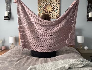Owner of Beets & Stitches holding up purple crocheted throw blanket 