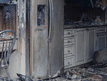 alt="Severe fire and smoke damage in Long Island kitchen with burned cabinetry"