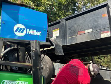 a ma repairing a trailer with a everlast welder next to him