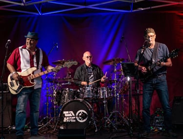 Live Bluesrock-Band performt auf der Bühne mit Drummer, Bassist und Gitarrist mit buntem Licht