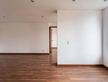 Sala de estar revestida em pladur, com piso laminado escuro, paredes brancas e iluminação natural.