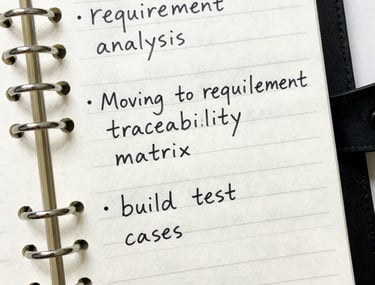 A detailed close-up of a professional planner and a high-quality pen on a dark desk. The paper shows structured notes and checkboxes, symbolizing organized testing phases and quality control.