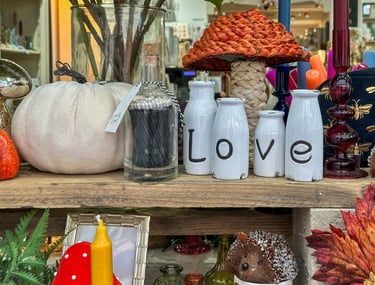 Rustic fall decor display with white pumpkins, match bottle, and Love ceramic bottles on a shelf.