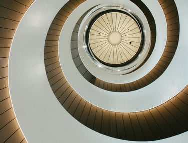 Low angle view of a modern spiral staircase with minimalist white walls and integrated lighting.