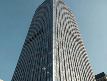 A perspective shot of a modern glass skyscraper in a North American city against a clear blue sky. The steel and glass facade represents scalability and high-tech efficiency.