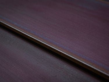 Close-up of high-quality industrial recycled steel plates with a subtle brushed texture, moody low-key lighting in deep aubergine and black, professional and authoritative tone.