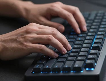 Close-up of hands typing on a modern mechanical keyboard with subtle blue backlighting in a dark, professional IT environment. Focus on precision and speed.