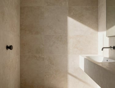 A serene bathroom interior with light beige stone tiles, soft natural light, and minimalist fixtures. South American &amp;#x2F; Brazilian setting.