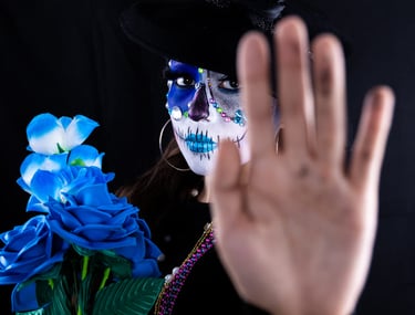 Mujer con maquillaje de calavera de azúcar del Día de Muertos sosteniendo rosas azules }