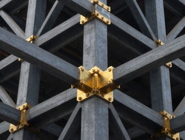 Close-up of golden steel joints and dark graphite beams in a modern skyscraper structure under construction, highlighting engineering precision.