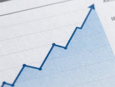 Macro photography of a financial report showing positive growth curves. The image is clean, sharp, and uses a professional palette of blues and grays.