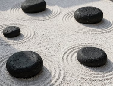 Top-down photography of a minimalist Zen rock garden with perfectly raked white sand and black basalt stones. Sunlight creates soft shadows. Hispanic / Japanese-inspired aesthetic.