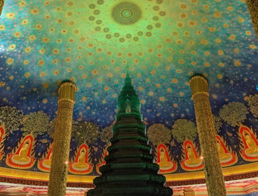 Intricate emerald glass stupa inside Wat Paknam Phasi Charoen temple with a celestial painted ceiling.