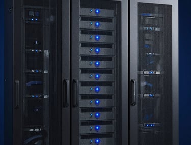 Clean, professional photograph of high-end server racks in a secure data center, with soft sky blue indicator lights against a deep navy blue background. North American / US infrastructure style.