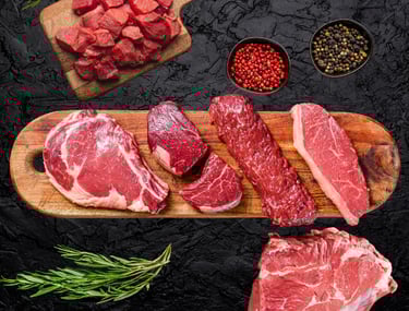 Bœuf halal cru : steaks et morceaux variés sur planche avec épices et herbes fraîches.