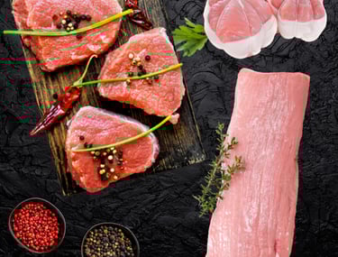 Veau halal cru : pavés et morceau entier assaisonnés avec herbes et épices sur planche.