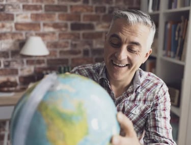Homem sorridente segurando globo terrestre, representando expatriados e mobilidade global.