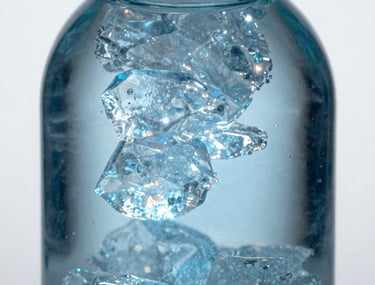 Macro photography of an elegant glass bottle refracting shimmering ice blue light, sharp focus on light play and liquid textures, sophisticated and professional, North American / US.