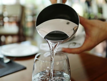 a person pouring water into a glass of water
