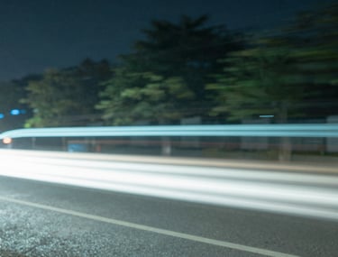 Abstract slow shutter photography of city lights at night, creating light trails in pale blue and sage green, high-concept aesthetic.