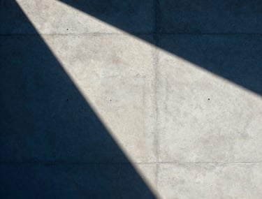 Abstract photography of architectural shadows on a concrete wall. Sharp lines, deep blue and crisp off-white tones, minimalist Latin American / Hispanic style.