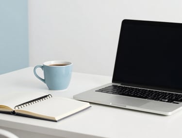 A minimalist workspace with a laptop and a notebook. A cup of coffee sits to the side. Bright, airy Latin American apartment studio. Colors dominated by ghost white and soft slate blue.