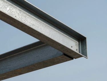 Close-up of a structural steel beam being placed with precision against a slate-blue sky during a custom residential build.