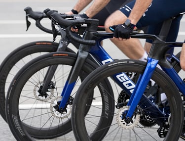 Close-up of high-end sports road bikes aligned at the starting line of a national tournament in Chisinau. Soft clean lighting, focus on precision carbon fiber frames, aerodynamic wheels, and deep patriotic blue accents.