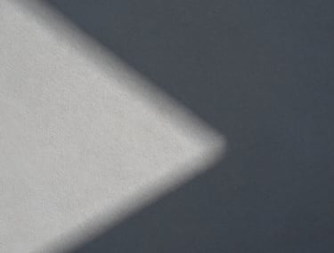 Abstract composition of light and shadow on a textured grey wall in Lisbon. Minimalist, artistic photography highlighting shape and form.